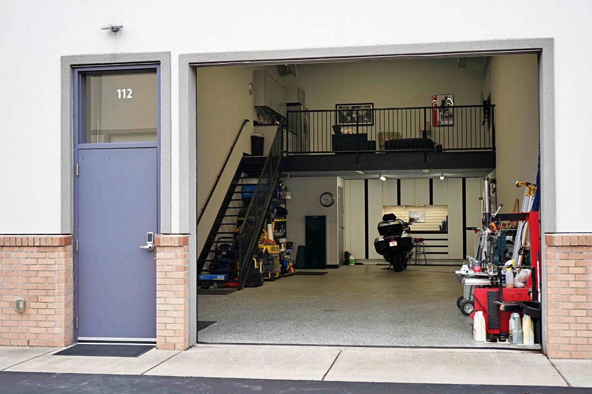 Open garage showing a workshop area on the ground floor and a mezzanine loft above.
