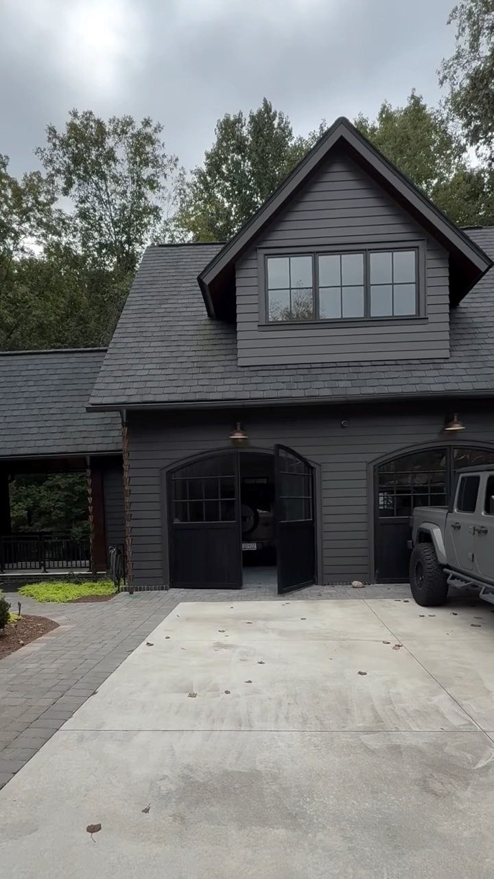 American House Garage Door: 7 Styles for Better Curb Appeal 1 Dark grey house featuring two arched black carriage-style garage doors under a gabled roof.
