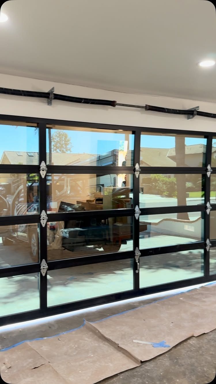 American House Garage Door: 7 Styles for Better Curb Appeal 4 Black framed glass garage door installed in a modern residential garage setting.