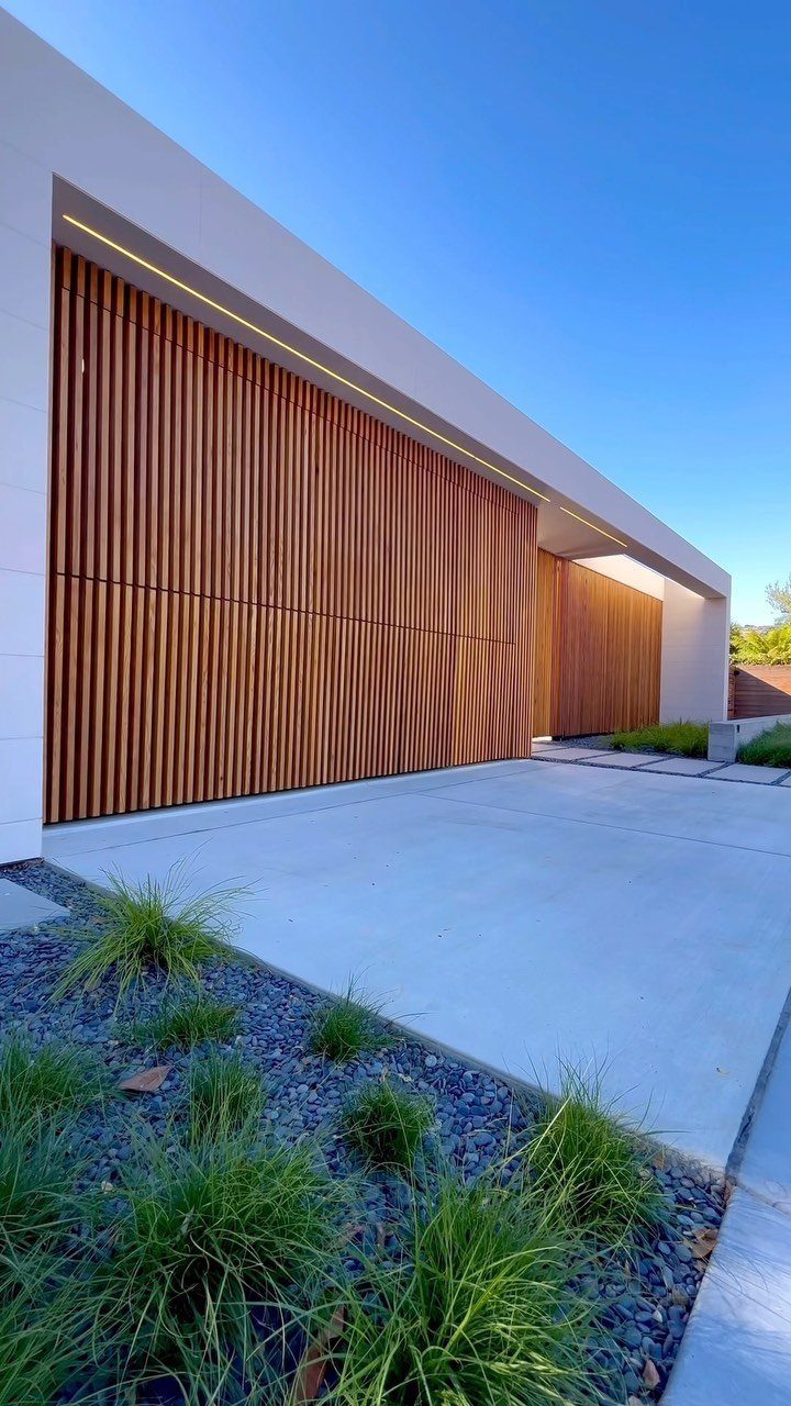 American House Garage Door: 7 Styles for Better Curb Appeal 6 Modern white house with large vertical wooden slat garage doors and a concrete driveway.