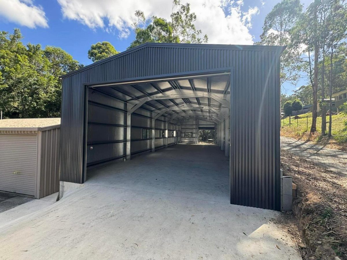 A large black corrugated metal garage with an open entrance and concrete floor.