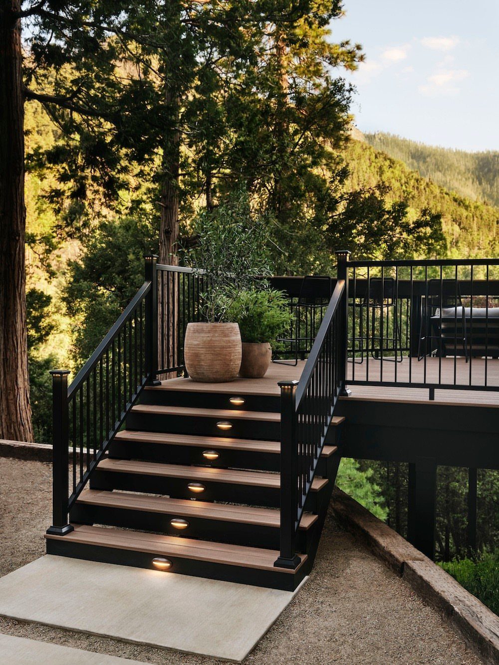 Deck Steps With Landing: 12 Ideas for Any Yard 3 Dark wooden deck steps with integrated lighting and black metal railings leading to a landing.