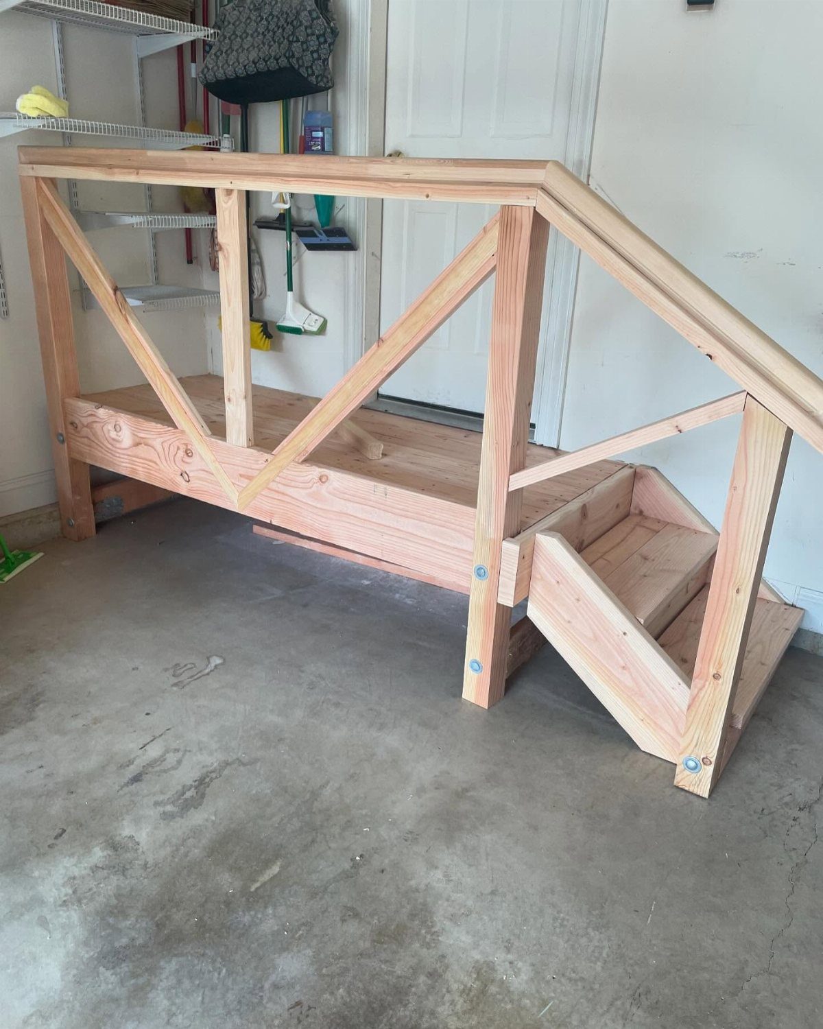 Deck Steps With Landing: 12 Ideas for Any Yard 11 Small wooden steps with a landing and handrail sitting on a concrete garage floor.