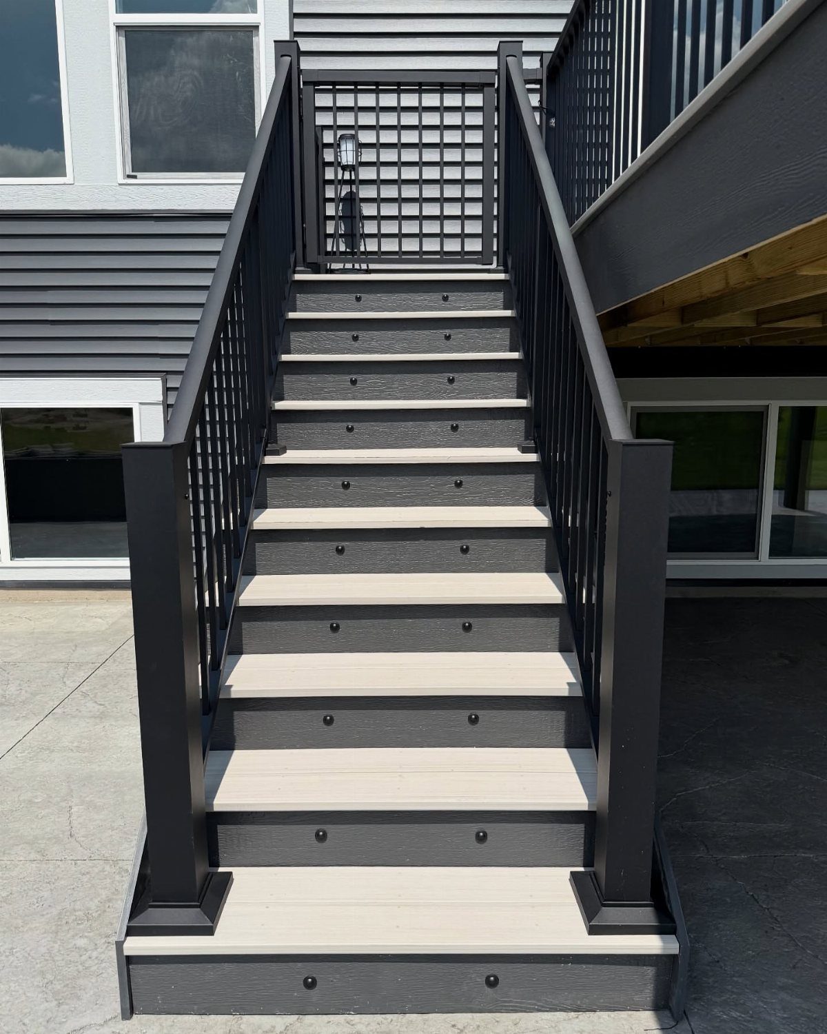 Deck Steps With Landing: 12 Ideas for Any Yard 9 Grey and black outdoor deck steps with black metal railings leading to a landing.