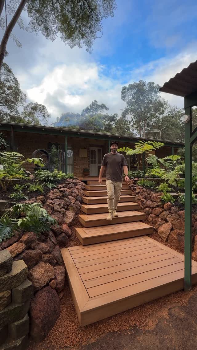 Deck Steps With Landing: 12 Ideas for Any Yard 8 Man walking down wide wooden deck steps towards a large timber landing in a garden.