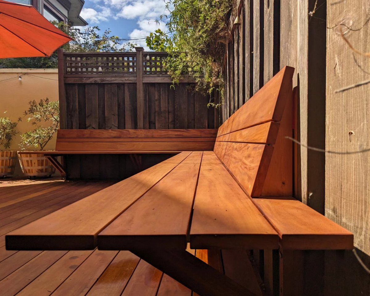Built-in wooden benches integrated into a deck next to a wooden fence.