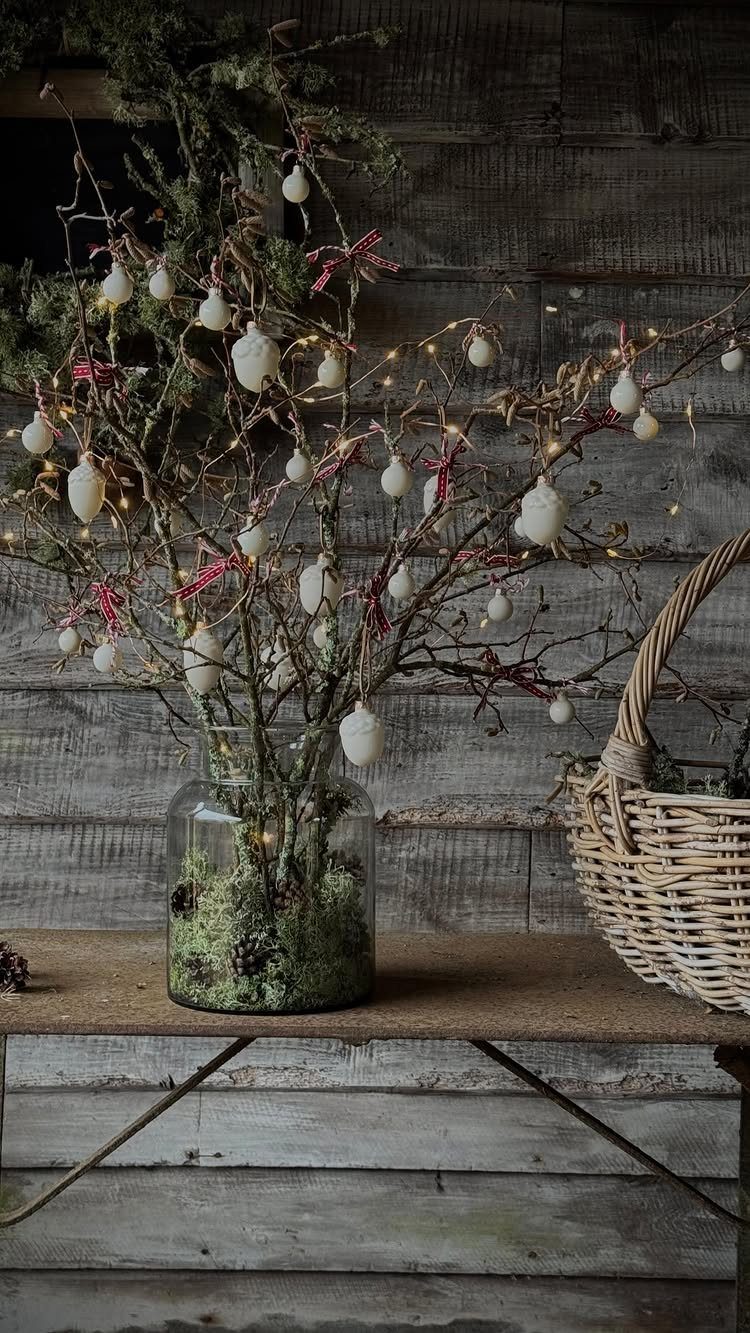 12 Decor for Winter After Christmas Ideas for a Cozy Home 7 Bare branches with white ornaments and lights in a moss-filled glass vase on a wooden table.
