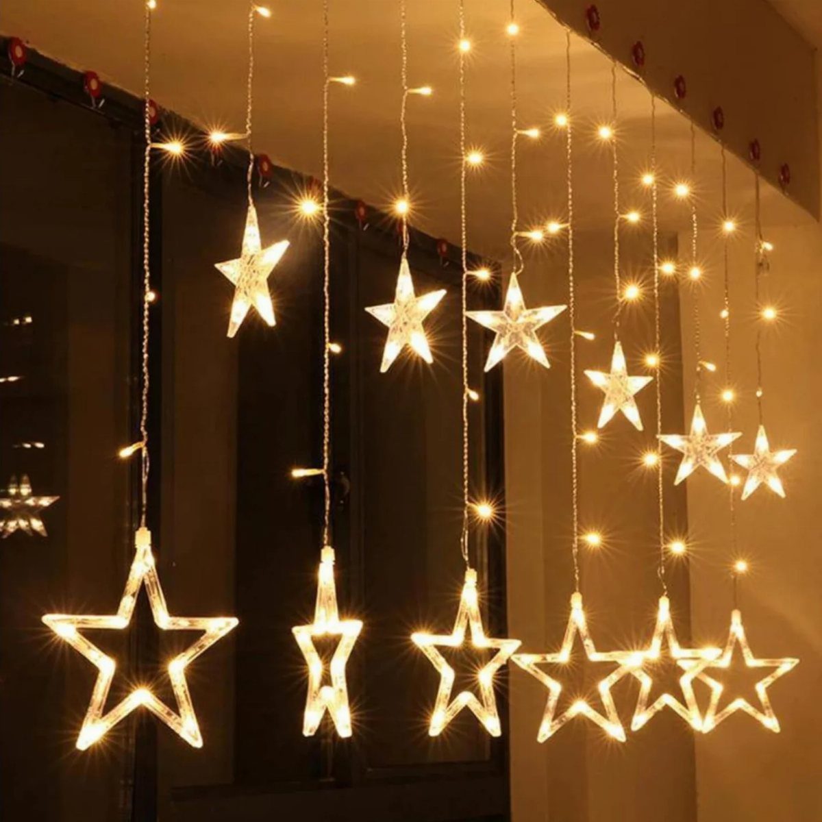 12 Decor for Winter After Christmas Ideas for a Cozy Home 3 Warm white star-shaped string lights hanging vertically against a dark window backdrop.