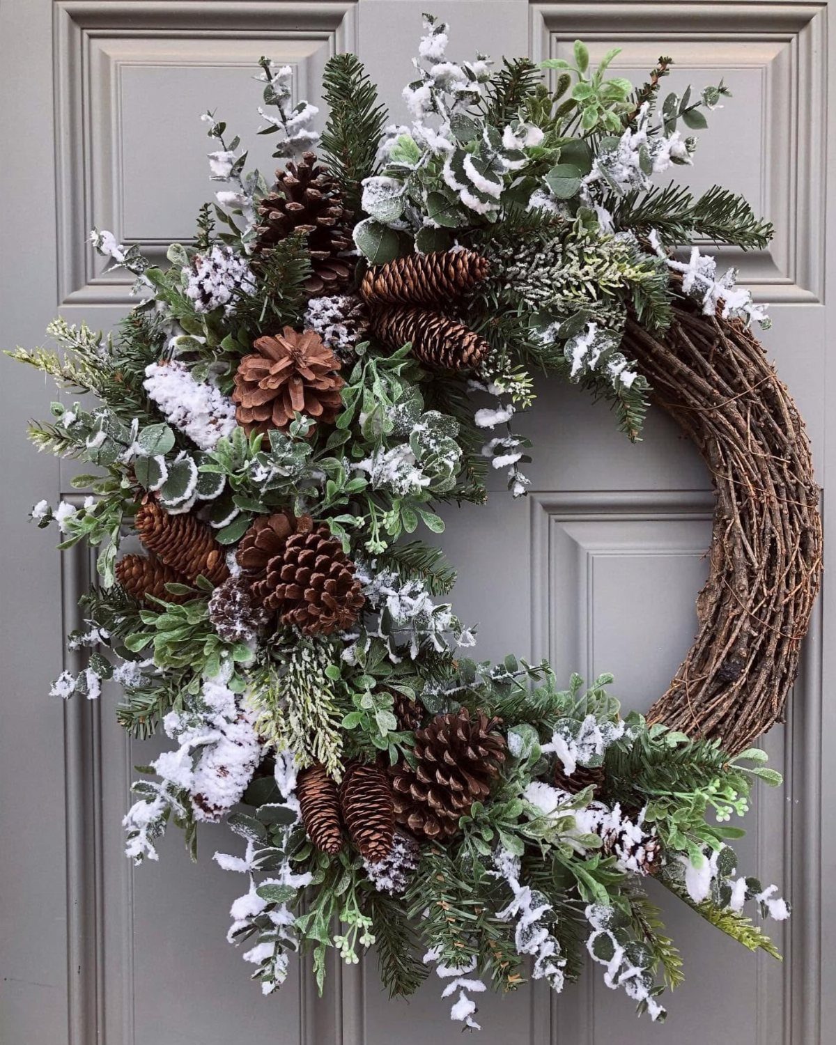 12 Decor for Winter After Christmas Ideas for a Cozy Home 6 A winter wreath with pinecones and frosted greenery hanging on a grey door.