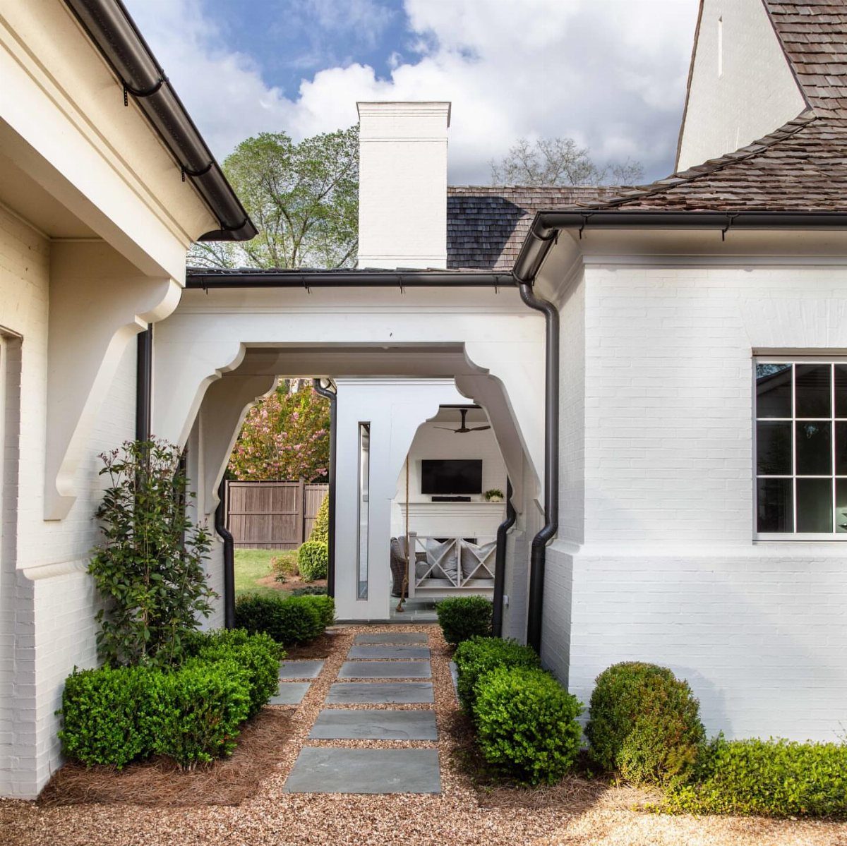Detached Garage with Breezeway to House: 8 Ideas 6 A white brick breezeway with an arched walkway and stone path connecting two buildings.