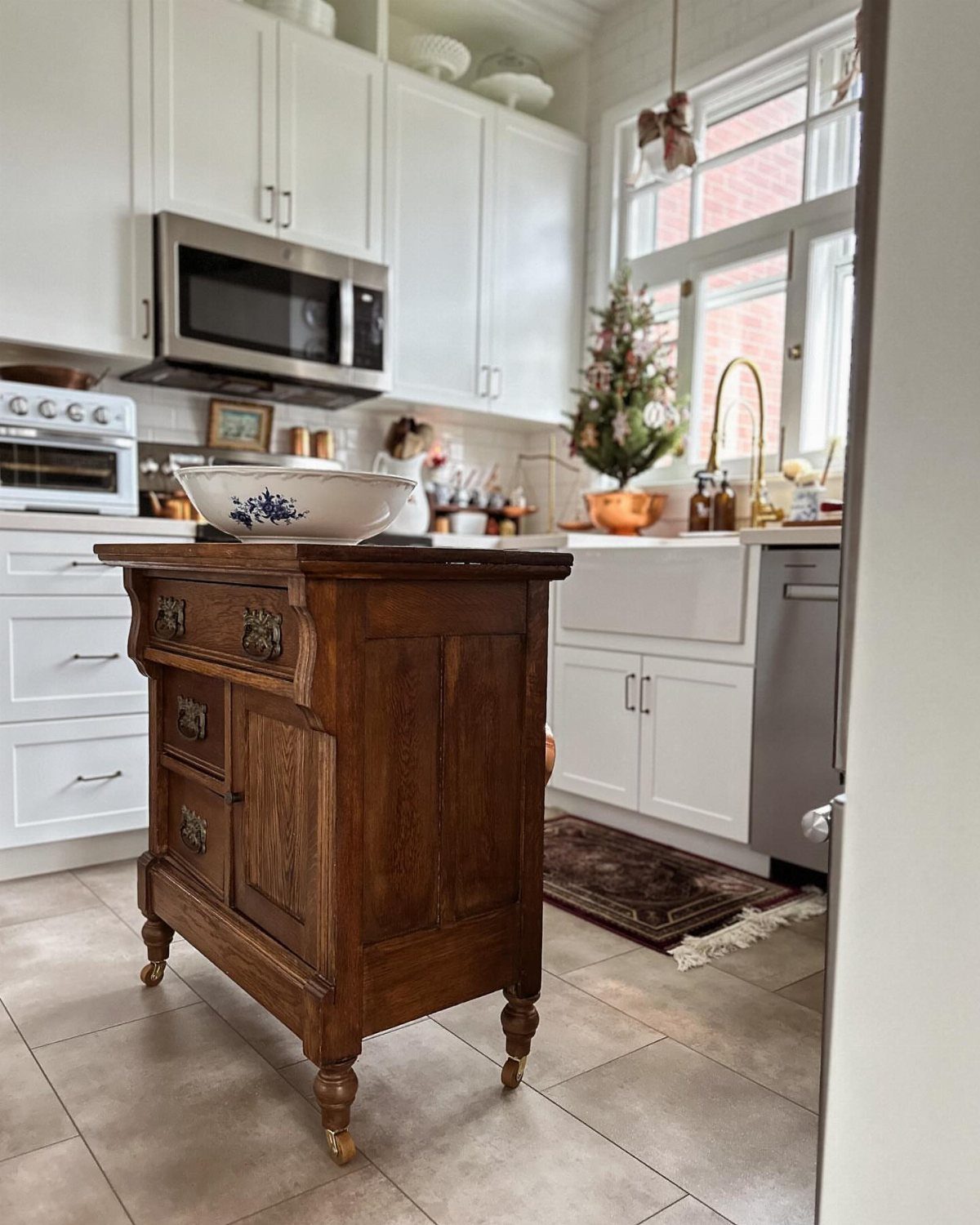 17 DIY Kitchen Island Ideas From Dressers to Live-Edge Slabs 1 Antique wooden dresser repurposed as a kitchen island in a bright white kitchen setting.