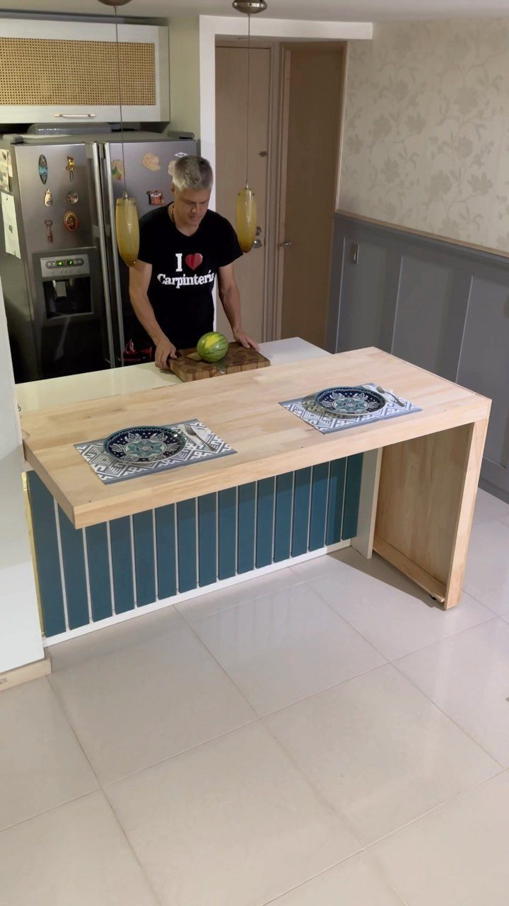 17 DIY Kitchen Island Ideas From Dressers to Live-Edge Slabs 2 A man standing behind a light wood butcher block kitchen island with a teal base.