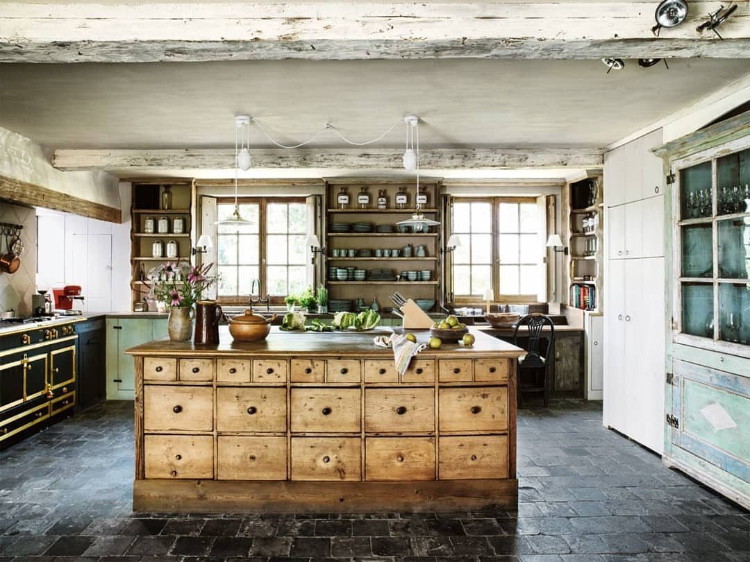 17 DIY Kitchen Island Ideas From Dressers to Live-Edge Slabs 6 A large rustic wooden kitchen island with many drawers in a farmhouse kitchen setting.