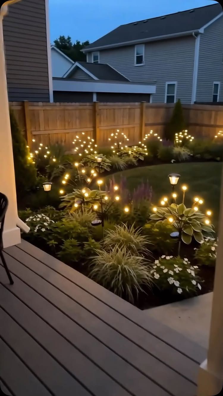 Garden flower beds illuminated by warm fairy lights and solar lamps at dusk.