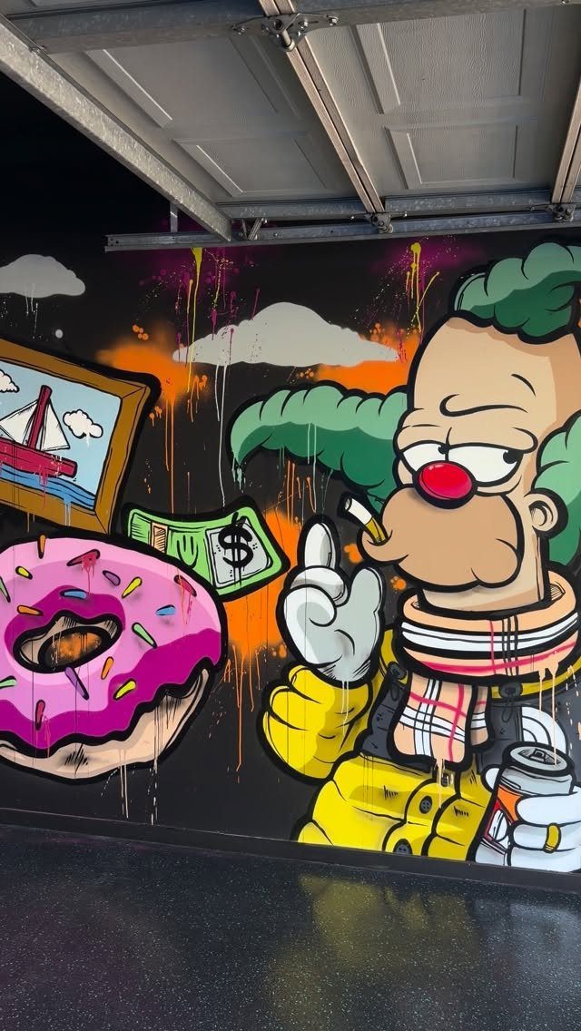 Colorful cartoon graffiti mural on a black garage wall featuring a character, a donut, and a sailboat.