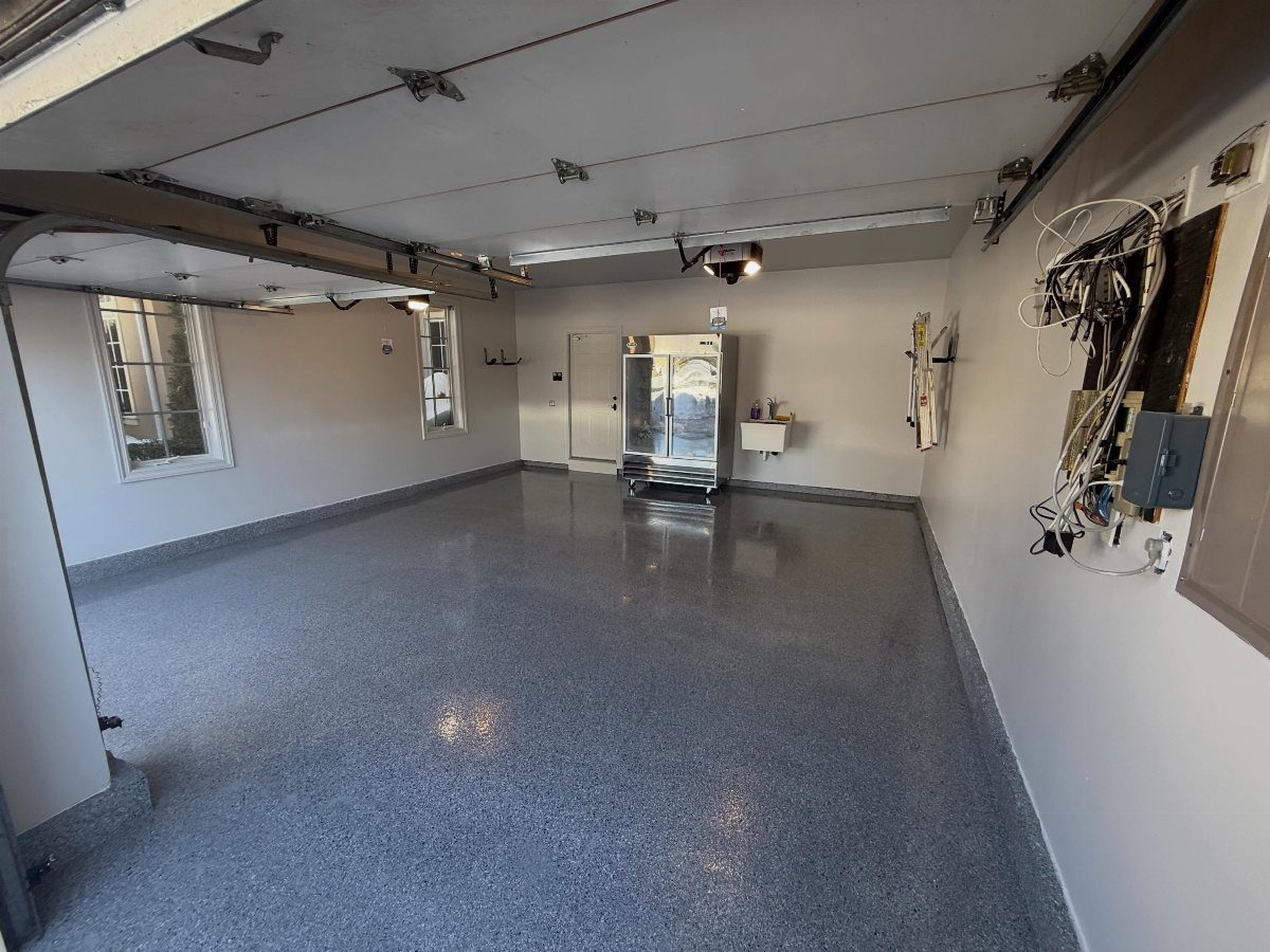 A clean garage featuring a blue-flecked epoxy floor and light gray walls.