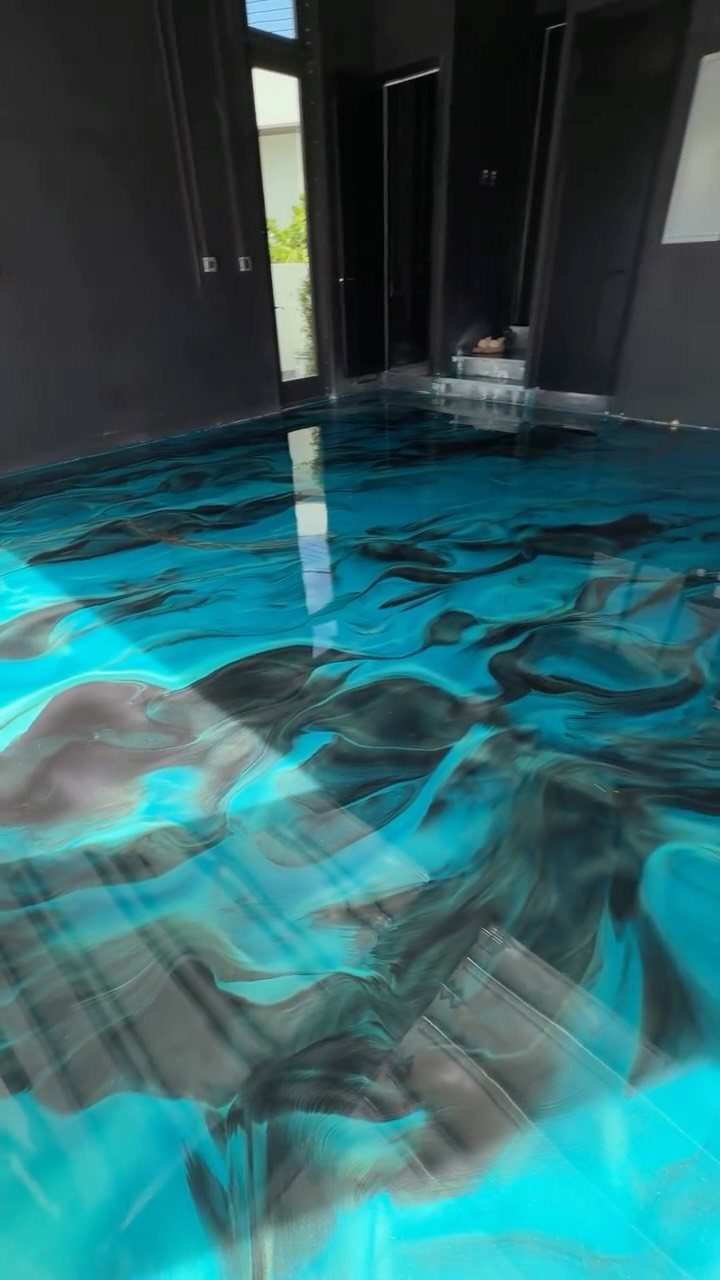Swirling turquoise and black epoxy resin coating on a highly reflective garage floor.