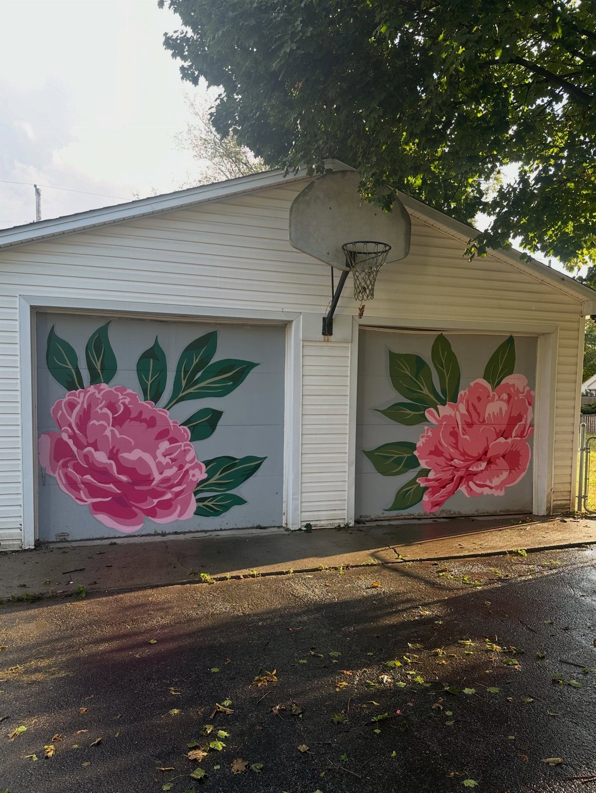 Two garage doors featuring large pink peony flower murals with green leaves on gray backgrounds.