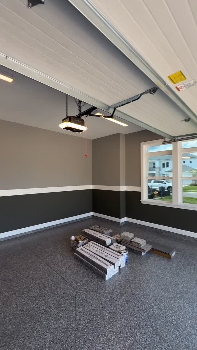 A garage with two-tone grey and white walls and a speckled epoxy floor.