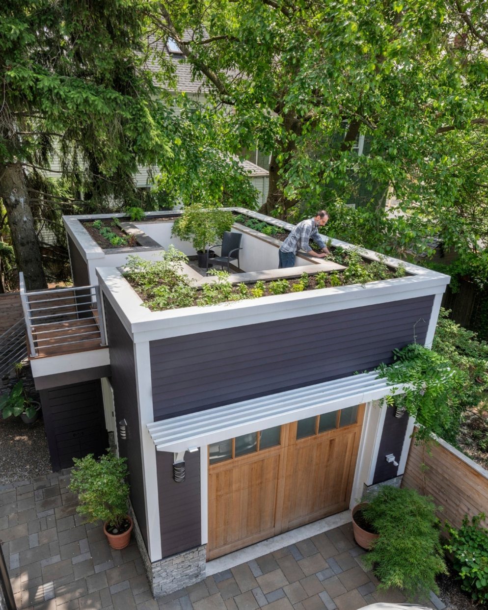 Garage Rooftop Deck: 8 Ideas for Your Space Above 2 A person tends to plants on a lush rooftop deck situated above a dark garage.