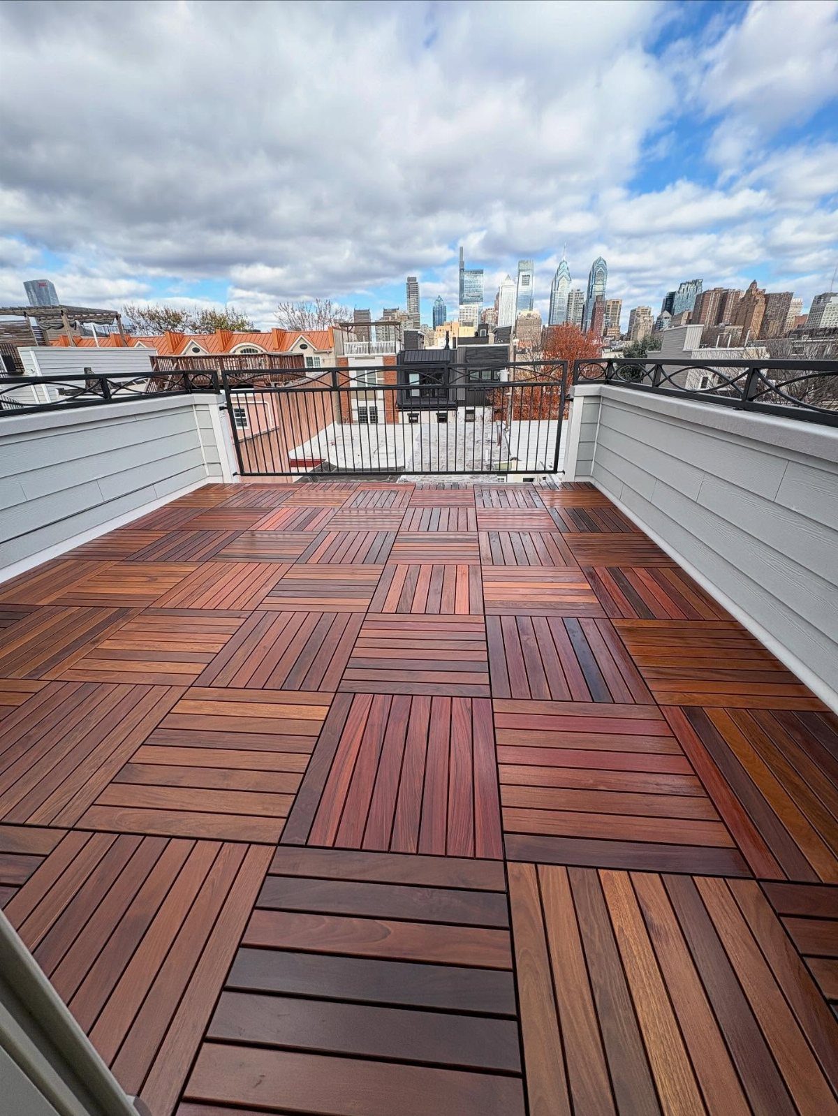 Garage Rooftop Deck: 8 Ideas for Your Space Above 3 Hardwood deck tiles in a multi-directional pattern on a rooftop overlooking a city skyline.
