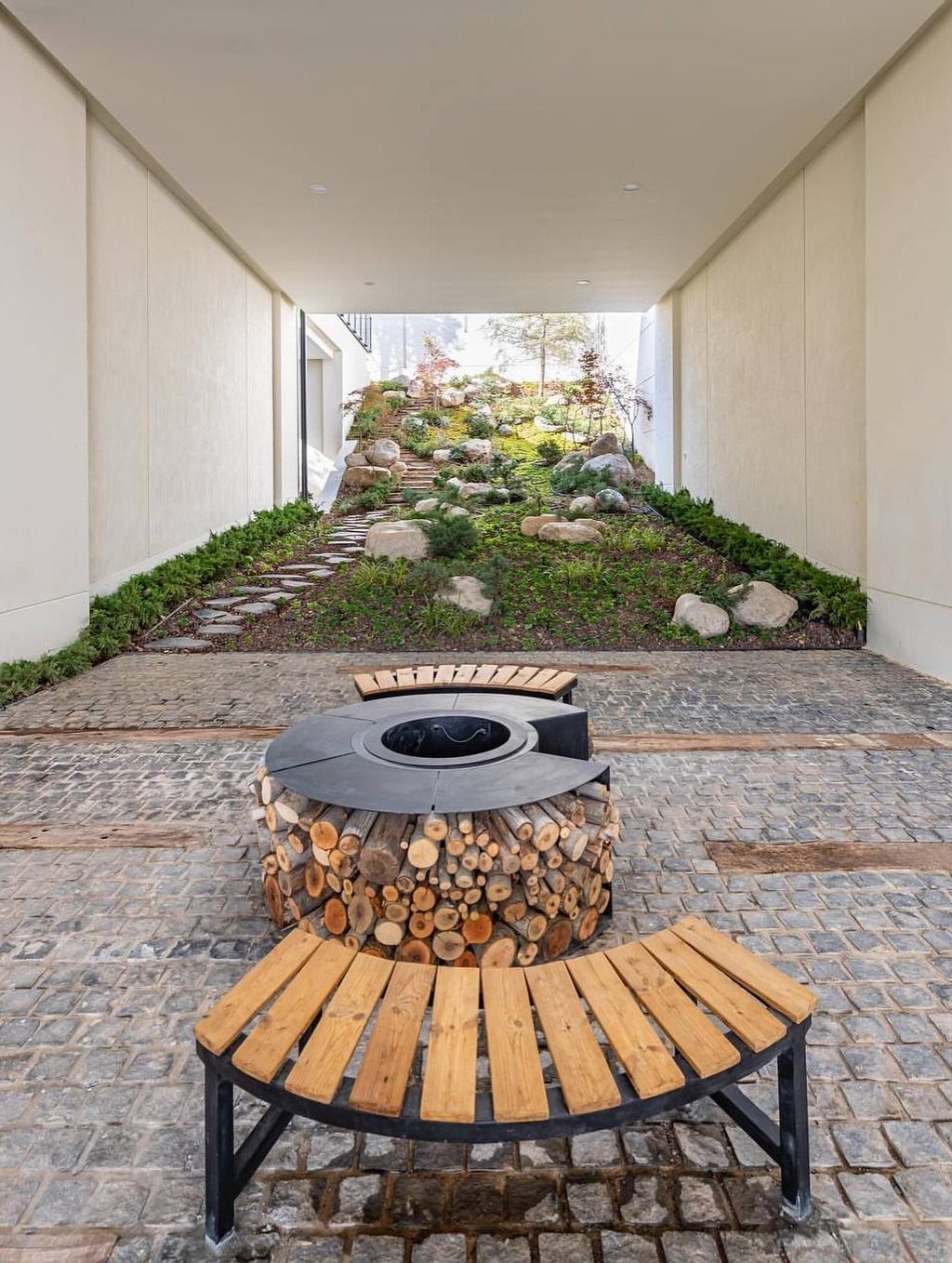 Landscaped garden with stone path and plants situated between two tall white building walls.