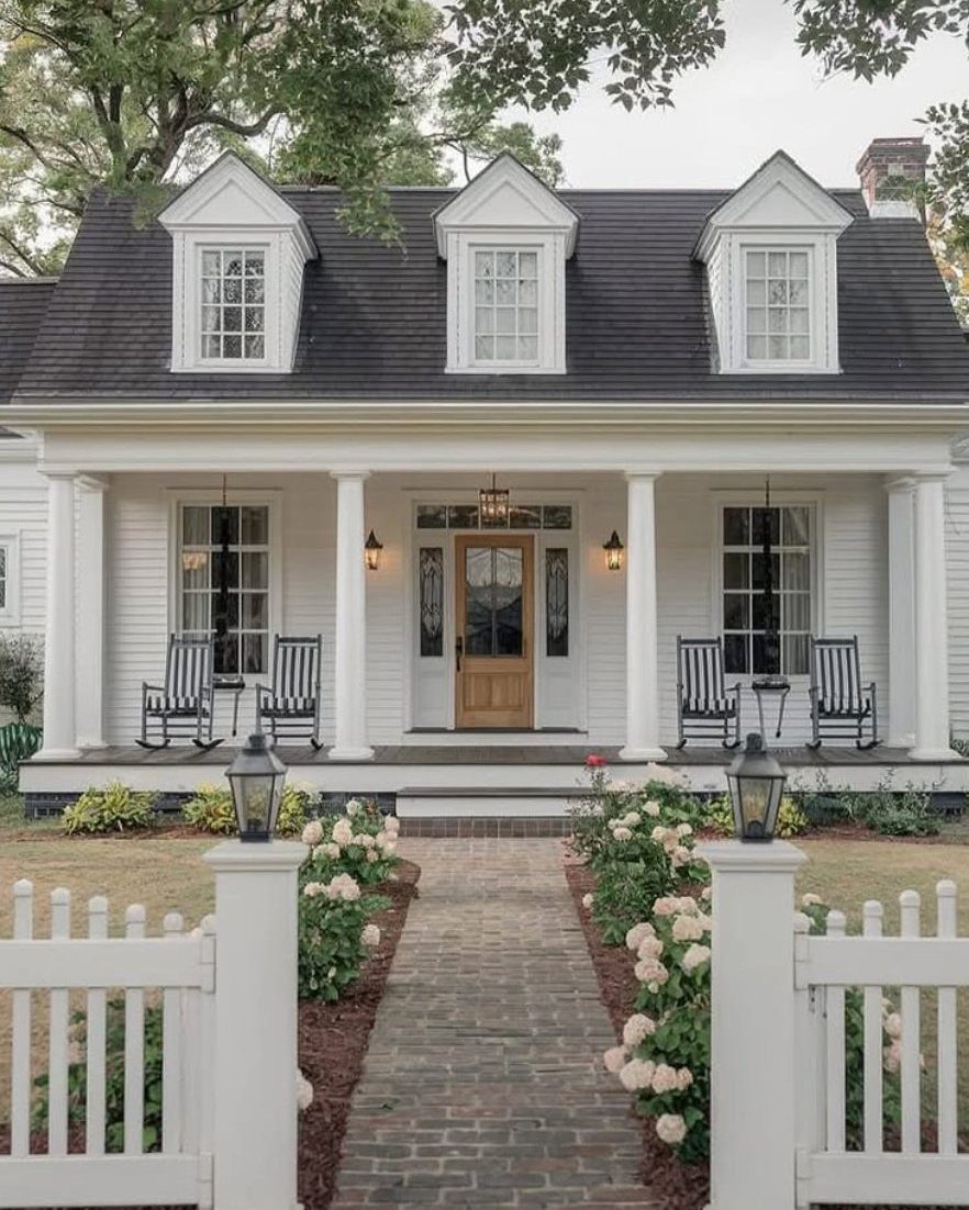 11 Landscaping Front Walkway Ideas: Flagstone to Paver & Modern Styles 5 A straight brick walkway lined with white roses leading toward a white house with a porch.