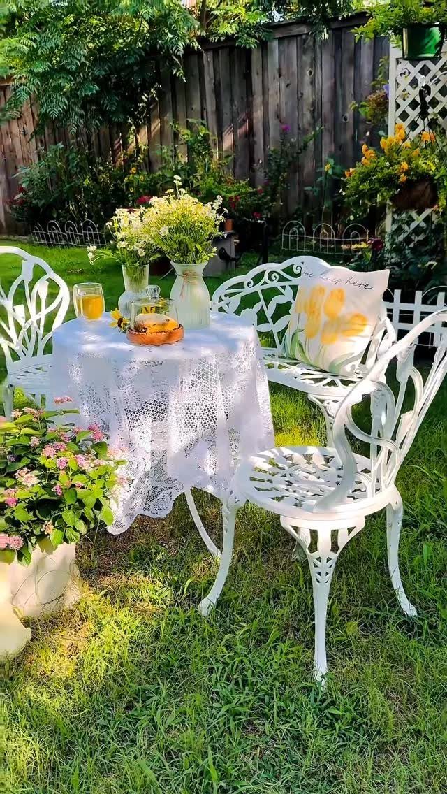 16 Low Budget Backyard Ideas to Refresh Your Outdoor Space 16 White metal garden furniture set with a lace tablecloth on a green lawn in a backyard.