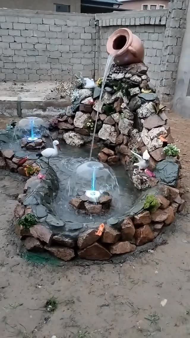 16 Low Budget Backyard Ideas to Refresh Your Outdoor Space 8 A stone water fountain with a terracotta pot pouring water into a small pool.