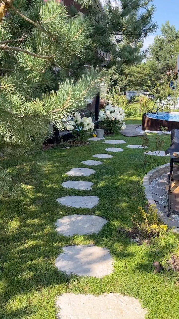 16 Low Budget Backyard Ideas to Refresh Your Outdoor Space 7 Light-colored flagstone stepping stones create a winding path through a green grass lawn.