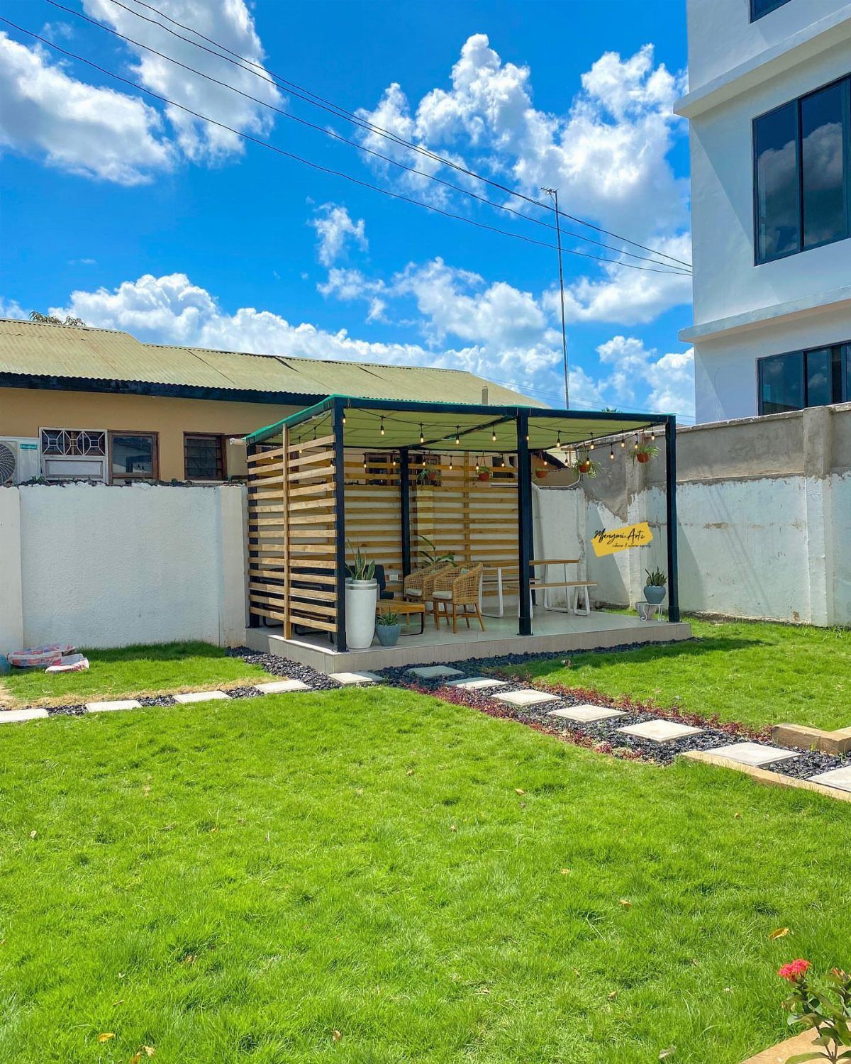 16 Low Budget Backyard Ideas to Refresh Your Outdoor Space 9 A modern black pergola with wooden slats enclosing a small outdoor dining area on a patio.