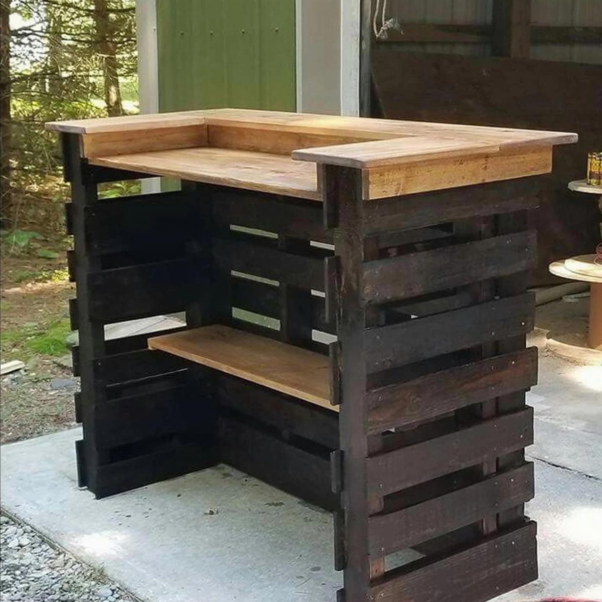 16 Low Budget Backyard Ideas to Refresh Your Outdoor Space 10 A handmade L-shaped outdoor bar constructed from dark wooden pallets and a thick light wood top.