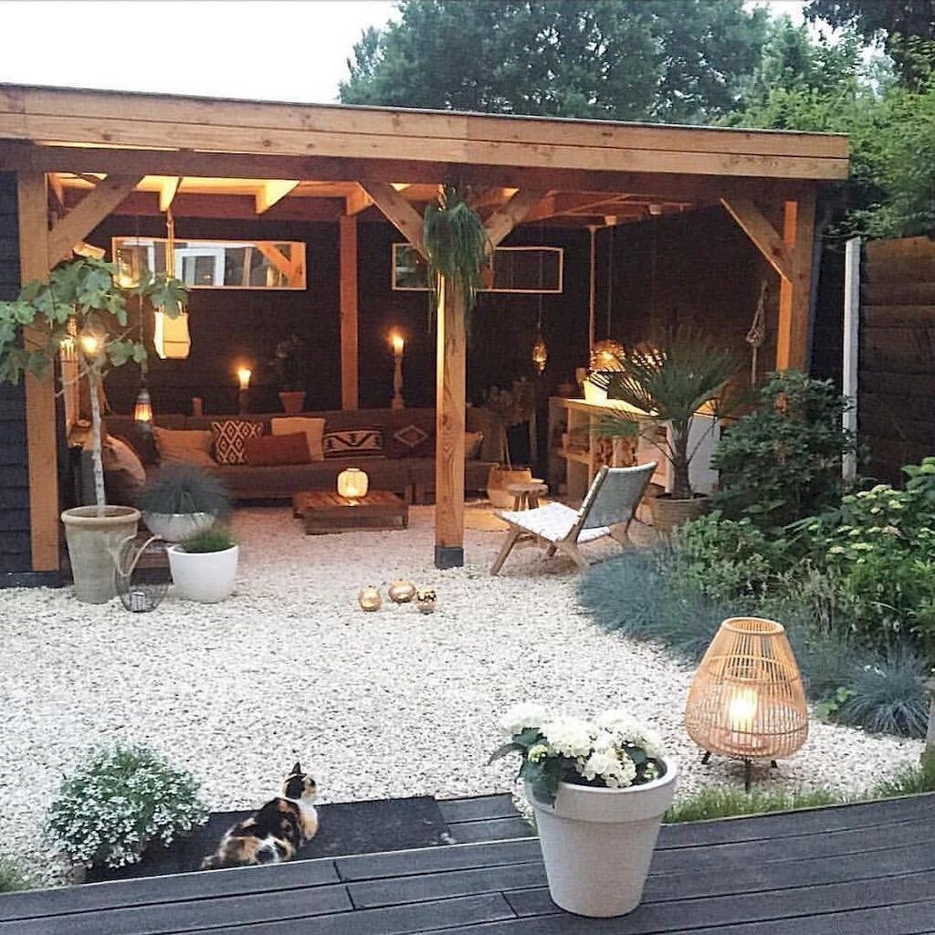 16 Low Budget Backyard Ideas to Refresh Your Outdoor Space 5 White gravel covers the ground of a backyard patio under a wooden pergola structure.