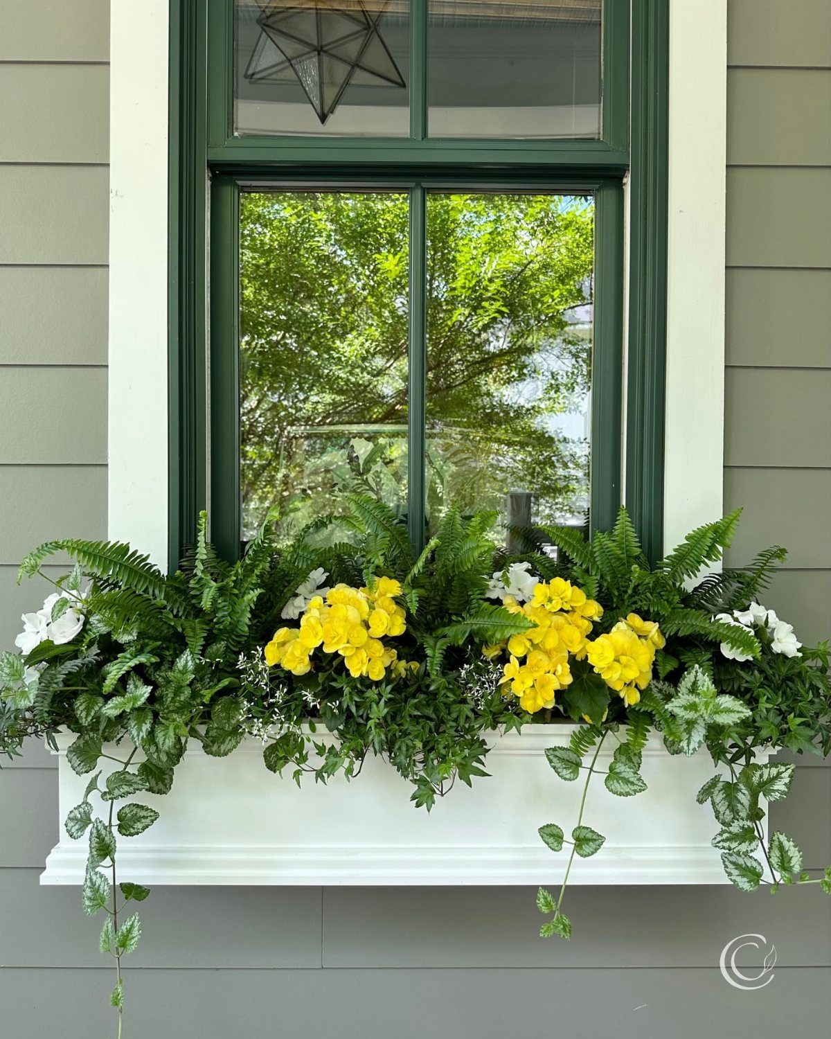 9 Outdoor Flower Pots Ideas with Window Boxes, Trellises & Wall Pots 2 White window box planter filled with green ferns and yellow flowers mounted under a green window.