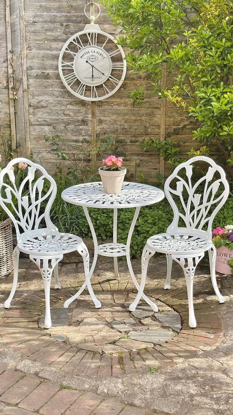White metal bistro set with two chairs and a small table on a brick patio.