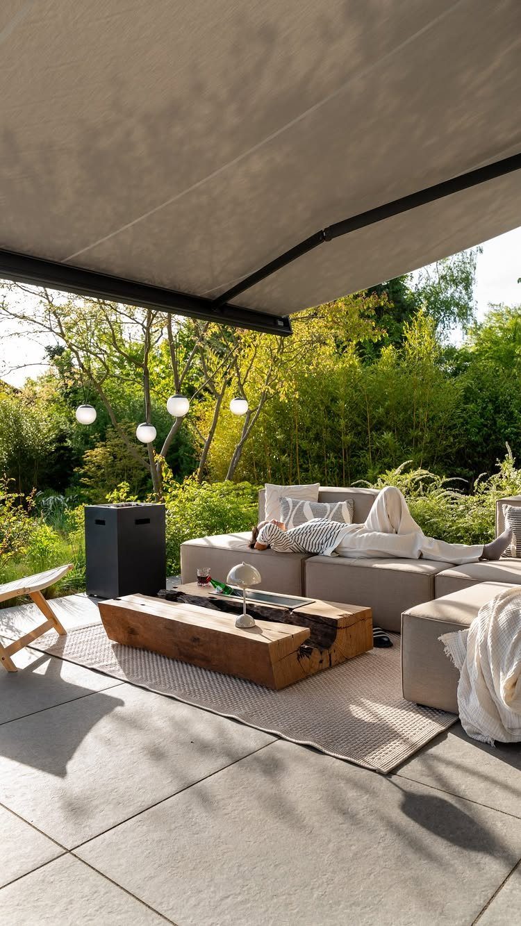 18 Yard Layout Ideas with Photos for Front and Back Spaces 8 A light grey outdoor rug sits under a wooden coffee table and sectional sofa on a patio.