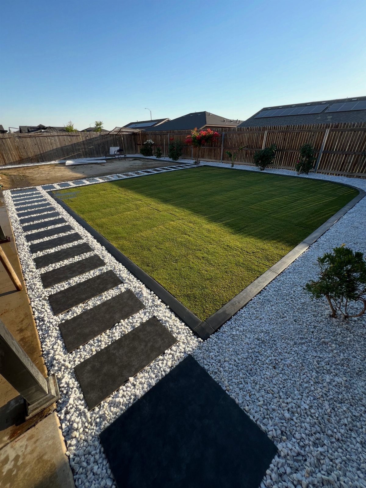 18 Yard Layout Ideas with Photos for Front and Back Spaces 6 White gravel walkway with large dark rectangular stepping stones bordering a green lawn.